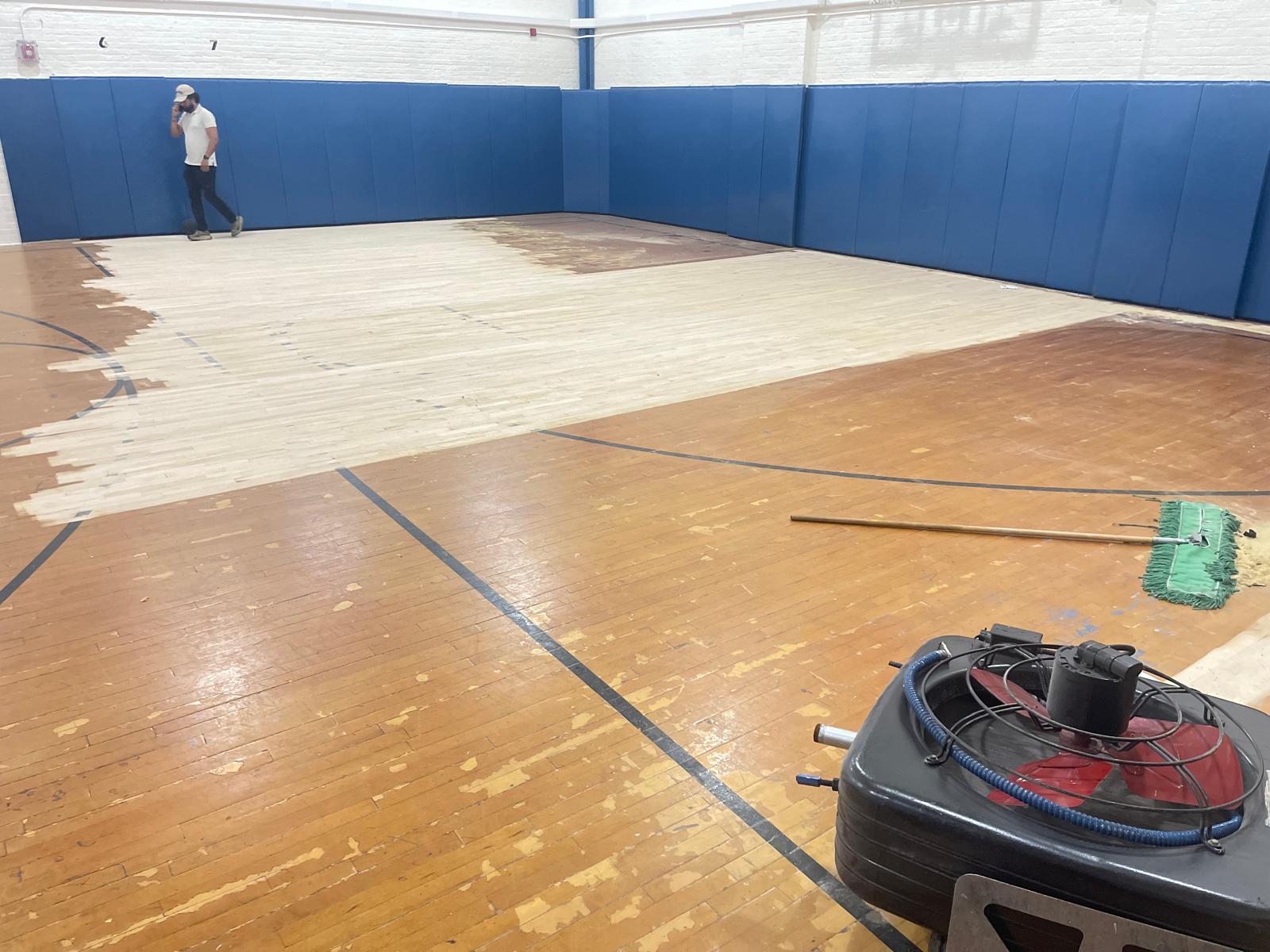 Restoration in progress — a section of the court sanded down to raw maple
